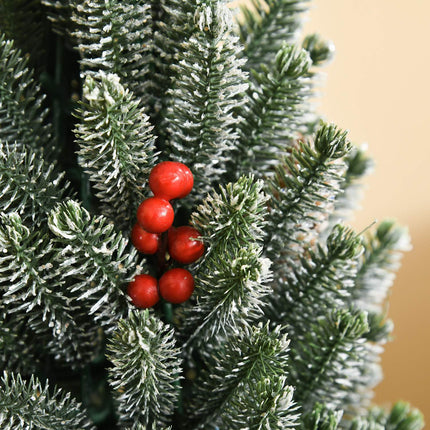 Snow-covered table Christmas tree with berries and pine cones