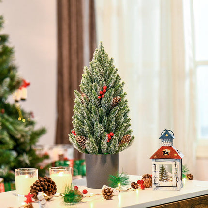 Snow-covered table Christmas tree with berries and pine cones